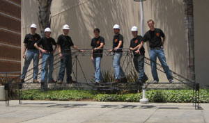 group wearing construction hats standing on small steel bridge